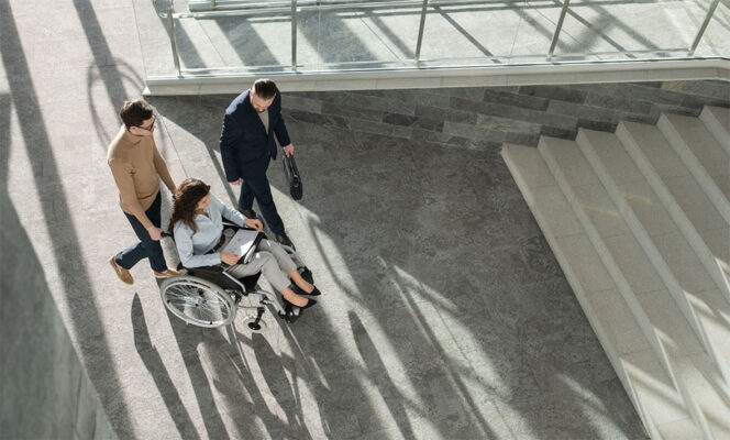 profissional em cadeira de rodas com colegas em ambiente corporativo, representando retenção de talentos pcd