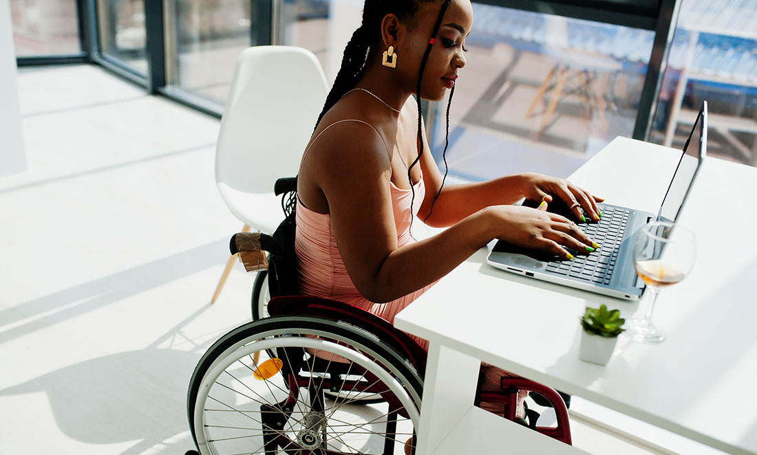 mulher-negra-cadeirante-trabalhando-em-escritorio-ilustrando-artigo-sobre-como-evitar-multa-demissao-pcd