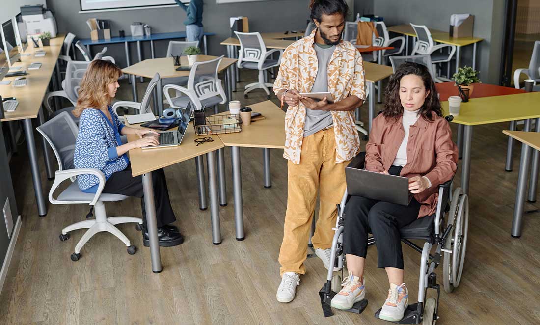 Pessoas diversas trabalhando juntas em um escritório acessível.